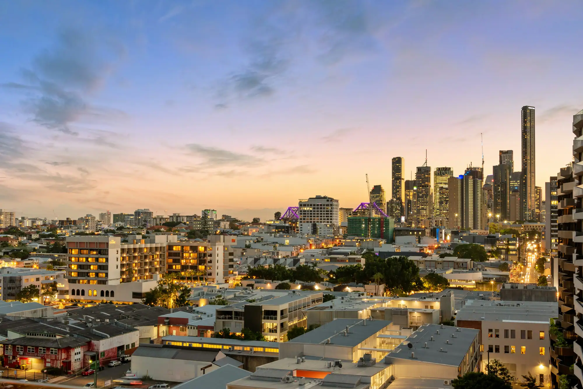 Aerial view of apartment buildings and hotels along a city beach, with the CBD skyline in the distance
